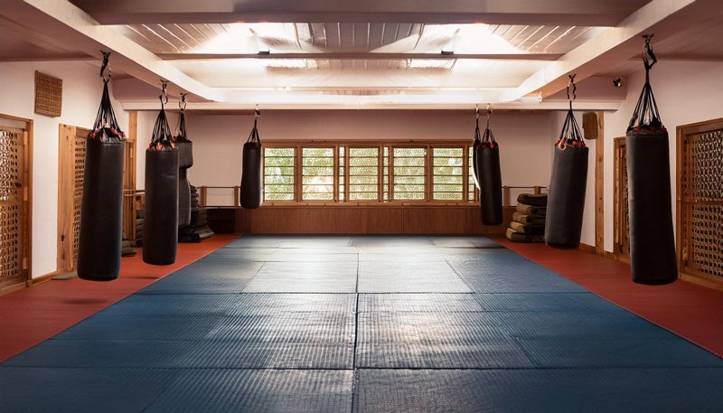 Spacious-martial-arts-studio-with-hanging-punching-bags-and-mats-for-martial-arts-web-design